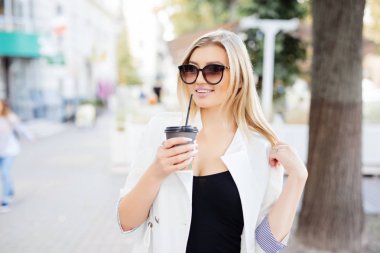 İçme kahve dışında kentsel arka plan üzerinde rahat şık kadın