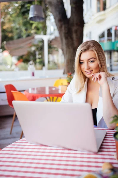 Bir kahve olan bir dizüstü bilgisayar ile Cafe'de güzel çekici kadın