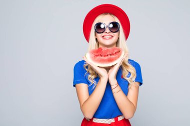 Yaz iyilik dilim. Dilim karpuz tutarak ve gri izole dururken gülümseyen güzel genç kadın