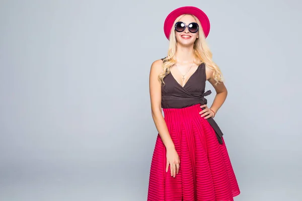 Hermosa mujer rubia hipster sonriente caucásica modelo en colores brillantes elegante y gafas de sol posando sobre fondo gris —  Fotos de Stock