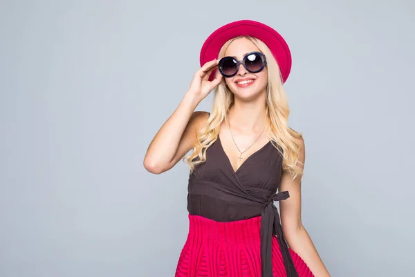 Bonito caucasiano sorridente hipster loira mulher modelo em cores brilhantes elegantes e óculos de sol posando em fundo cinza — Fotografia de Stock