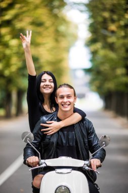 Eğlenceli ile sürme. Güzel genç çift sürme scooter silah yükseltmek ve gülümseyen mutlu kadın birlikte. Sürüş ve aşk
