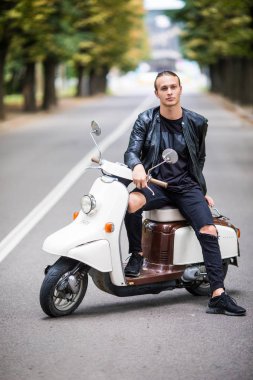 Siiting scooter sokak şehir üzerinde genç adam