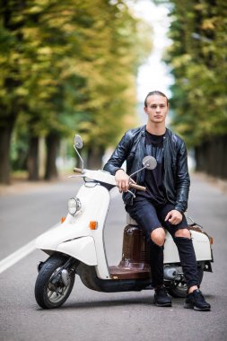 Siiting scooter sokak şehir üzerinde genç adam