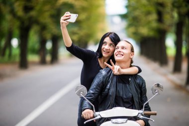 Genç çift selfie fotoğraf Smartphone'da yapma scooter üzerinde gülümseyen