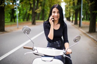 Genç mutlu kadın cep telefonu scooter üzerinde söz
