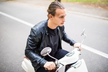 Kask içinde neşeli genç adam scooter şehirdeki sokak üzerinde biniyor.