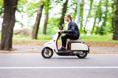 Yakışıklı bir adam bir motosiklet şehirdeki sokak hızına sürme yan görünüm