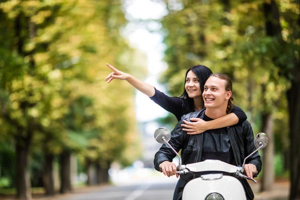 Belo jovem casal montando scooter juntos, mulher feliz apontando para longe . — Fotografia de Stock