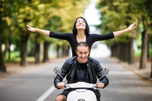 Счастливая молодая пара путешествует на скутере по старому европейскому городу. Женщина любит путешествовать с поднятыми руками — стоковое фото