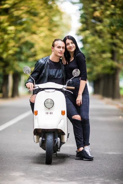 Couple sitting on scooter together and possing on the city street
