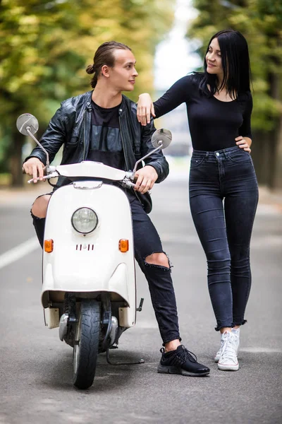 Güzel genç çift konuşmak ve açık havada scooter üzerinde otururken gülümseyen