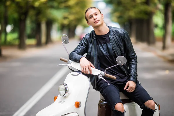 Siiting scooter sokak şehir üzerinde genç adam
