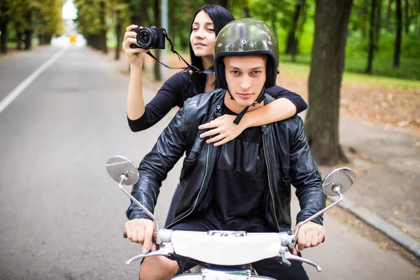 幸せ観光スクーターの若いカップル。屋外に乗りながらカメラで写真を作る女性 — ストック写真