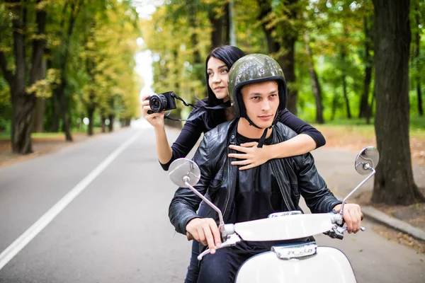 Счастливая молодая пара туристов на скутере. Женщина делает фото на камеру во время езды на открытом воздухе — стоковое фото