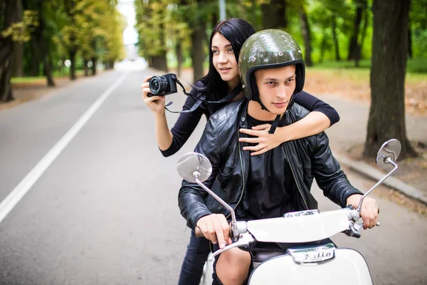 Счастливая туристическая молодая пара на скутере в новом городе. Женщина делает фото на камеру во время езды на открытом воздухе — стоковое фото