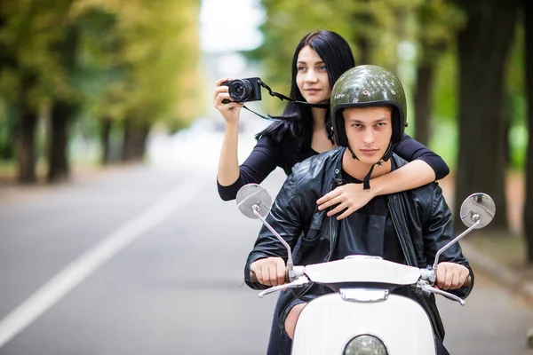 Scooter üzerinde mutlu turist genç çift new city'binmek. Açık havada sürme sırasında kamera fotoğraf yapma kadın