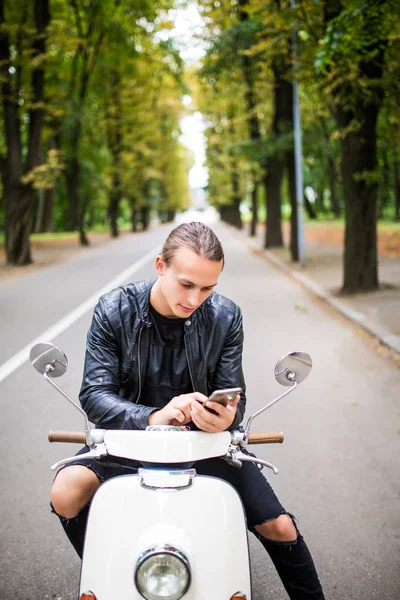 携帯電話でメッセージを入力してバイクに座っているハンサムな男 — ストック写真