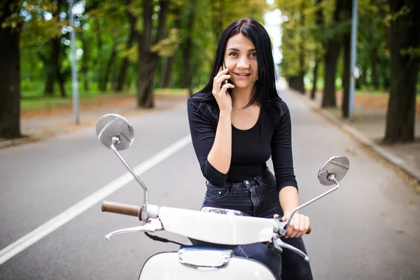 Jovem mulher feliz falando telefone celular em scooter — Fotografia de Stock