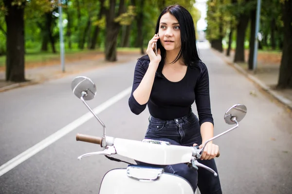 Genç mutlu kadın cep telefonu scooter üzerinde söz