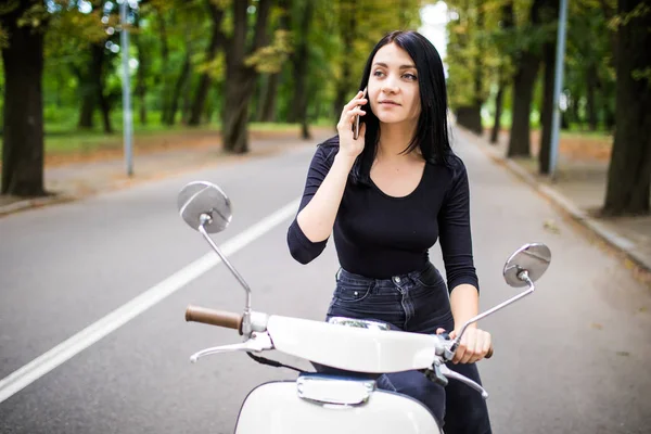 Rahat scooter üzerinde oturan ve Evet güzel genç kadın giyinmiş.