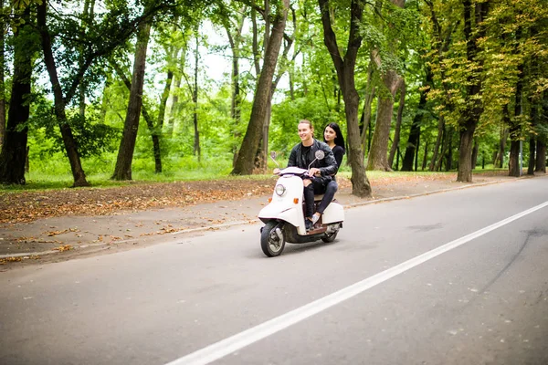 Красивая молодая пара катается на скутере вместе, женщина обнимает своего парня. Вид сбоку на скорость . — стоковое фото