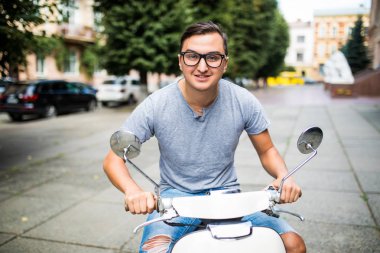 Genç adam sokakta vintage bir scooter sürme.