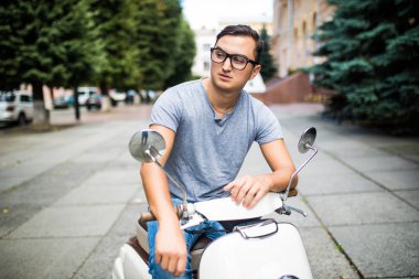 Vintage bir scooter sokakta oturan genç yakışıklı adam