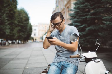 Tipik bir haber telefonda scooter üzerinde oturan yakışıklı mutlu adam