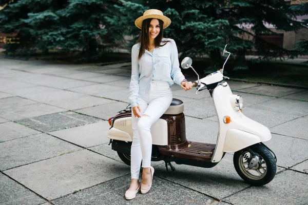 Ung kvinna sitter på moto scooter på smal gata i gamla stan. — Stockfoto