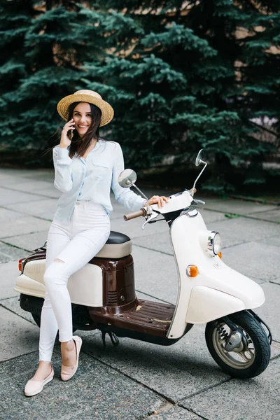 Jovem mulher feliz usando telefone celular na ciclomotor — Fotografia de Stock
