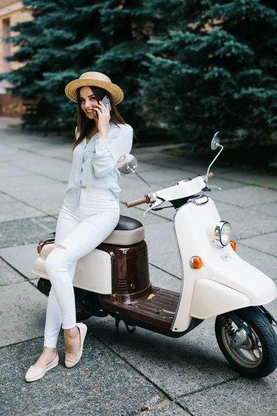 Motosiklet üzerinde cep telefonu kullanan genç mutlu kadın