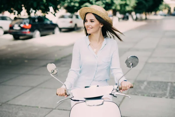 Retrato de uma bela garota dirigir em scooter retro, sorrindo e olhando para a câmera — Fotografia de Stock