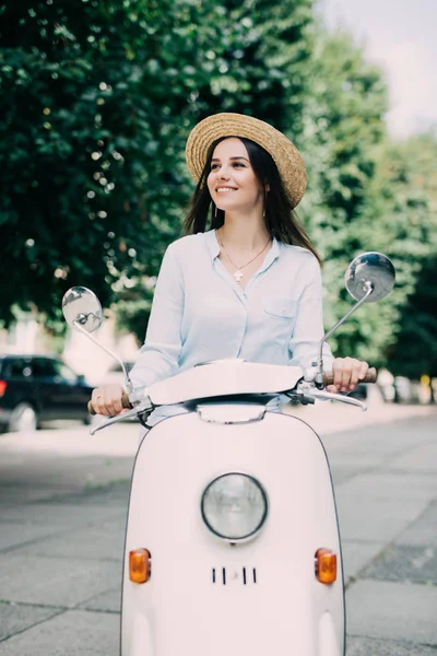 Jovem e bela mulher excitada andando de scooter ao longo da rua — Fotografia de Stock