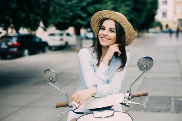 Menina bonita em um chapéu em uma camiseta branca e chapéu posando em uma scooter — Fotografia de Stock