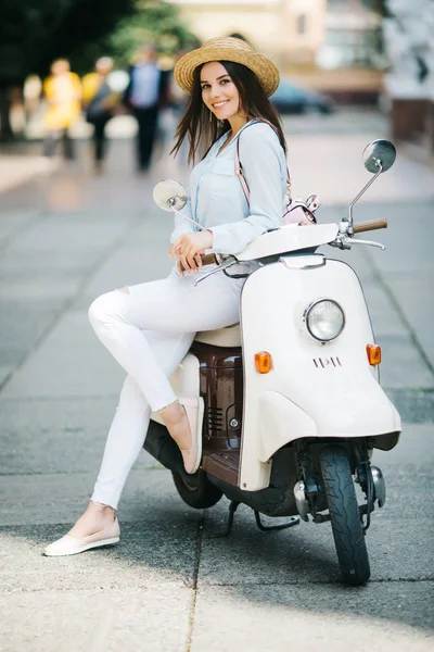 Счастливая молодая женщина на улице, стоящая рядом со скутером. Смотря какая камера . — стоковое фото