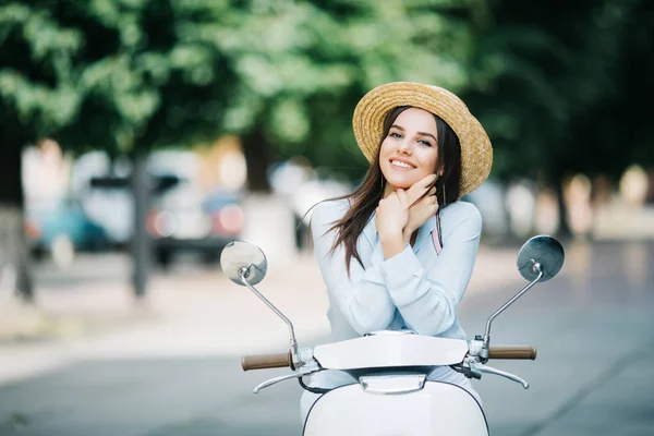 Giovane donna alla moda in abito casual seduto su scooter per strada . — Foto Stock