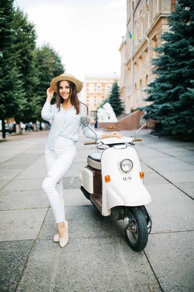 Eski şehrin dar sokakta moto scooter üzerinde oturan genç kadın.