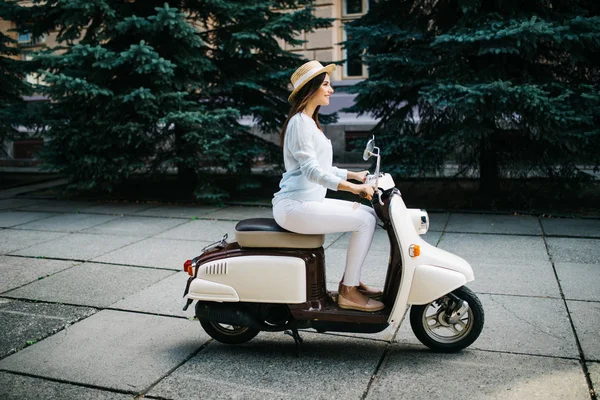 Jovem mulher sentada na moto scooter na rua estreita na cidade velha . — Fotografia de Stock