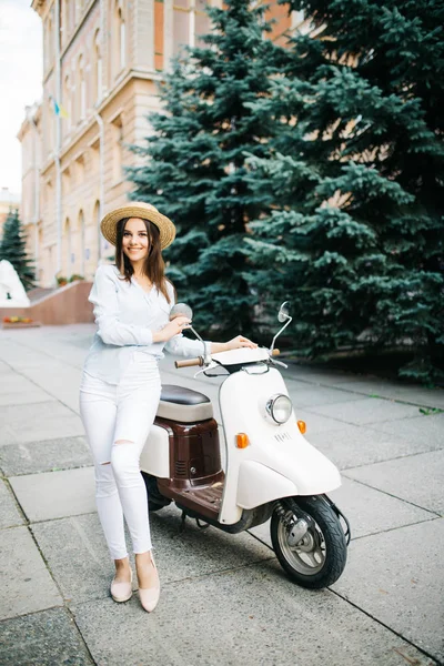 Jovem mulher em roupa casual sentado em scooter na rua . — Fotografia de Stock
