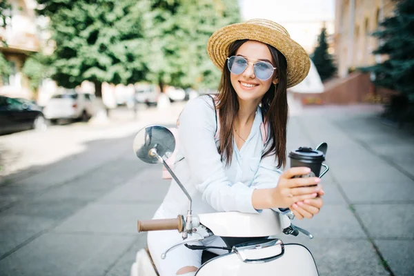 Menina feliz no sol de primavera bebe café, em scooter — Fotografia de Stock