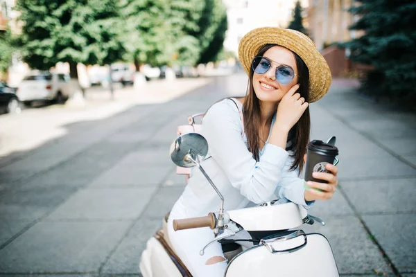 Jovem mulher bebendo café takeaway perto de seu ciclomotor na parte da manhã — Fotografia de Stock