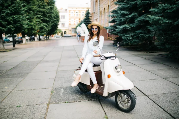 Молодая женщина в повседневной одежде сидит на скутере на улице . — стоковое фото