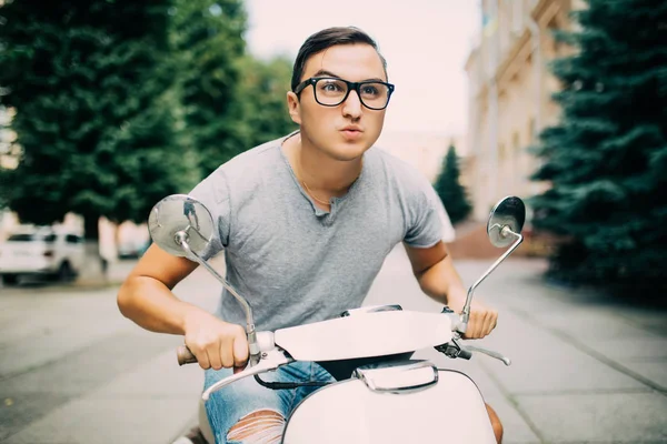 Genç adam sokakta vintage bir scooter sürme.