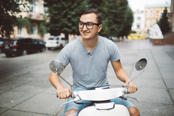 Jovem alegre sentado em scooter e falando no telefone celular — Fotografia de Stock