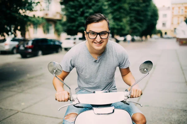 Scooter üzerinde oturan ve cep telefonda konuşurken neşeli genç adam