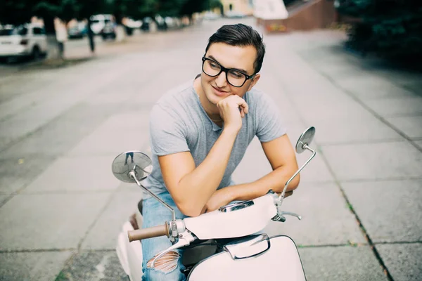 Молодой красивый мужчина сидит на винтажном скутере на улице — стоковое фото