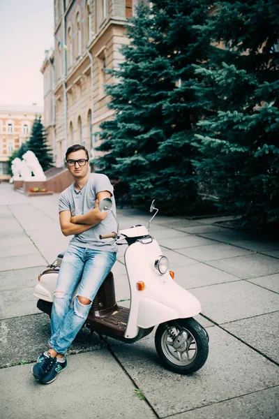 Scooter şehrin sokak üzerinde oturan yakışıklı genç adam