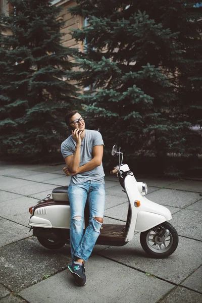 Jovem alegre sentado em scooter e falando no telefone celular — Fotografia de Stock