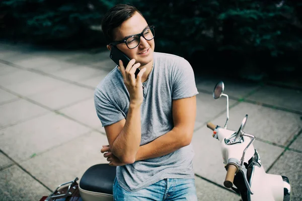電話で話しているバイクに腰掛けた若い美しさハンサムな男 — ストック写真